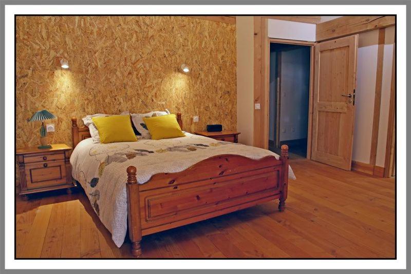 CerdonLES CHAMBRES DE LIANE的一间卧室配有一张带两个黄色枕头的木床