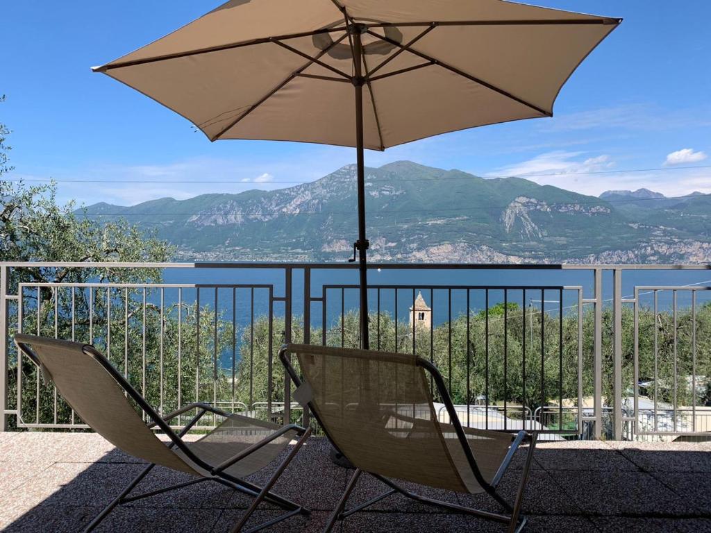 布雷佐内加尔达Camping Le Maior的阳台的一把带遮阳伞的椅子
