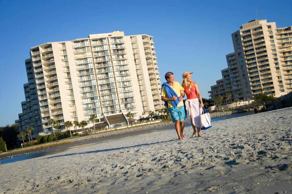 默特尔比奇大洋小溪度假酒店的两名妇女在大楼前的海滩上行走