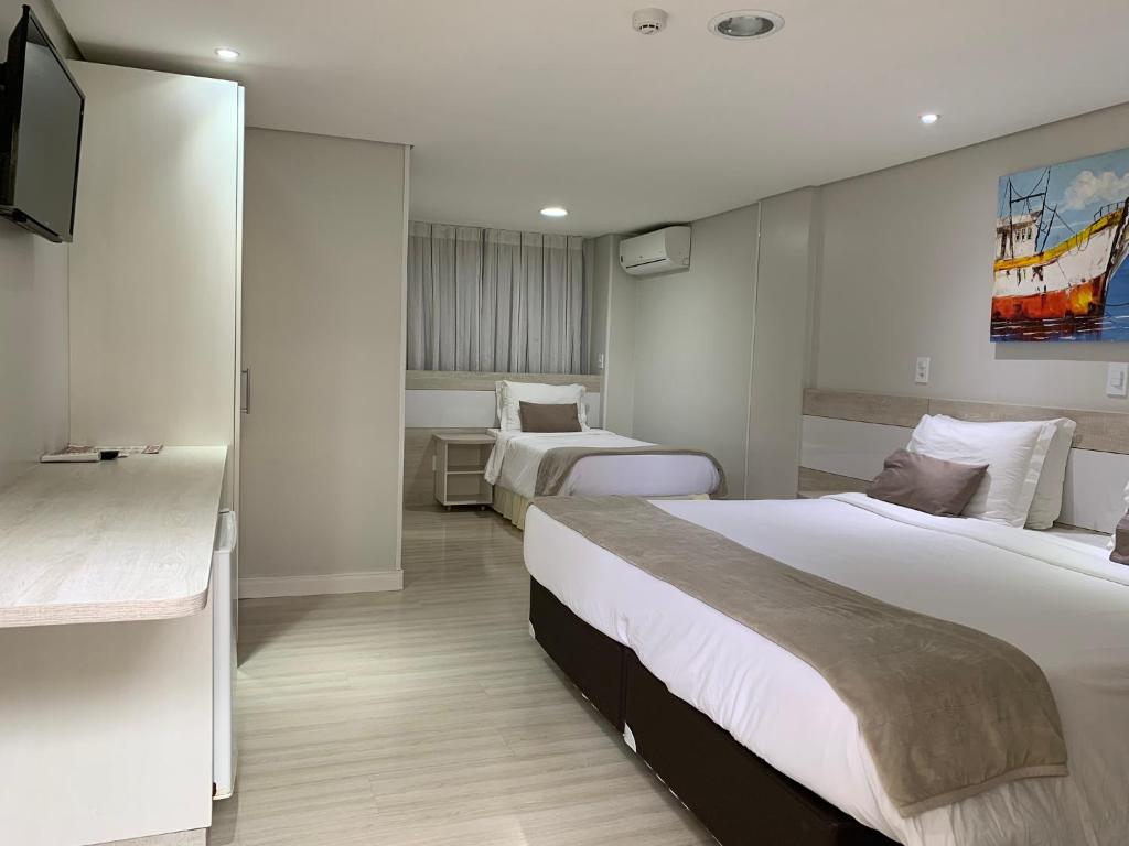皮拉图巴Hotel Recanto Do Rouxinol的酒店客房设有两张床和电视。
