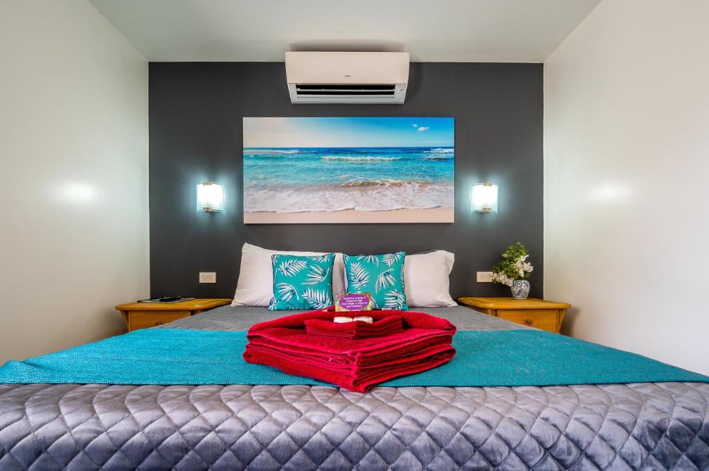 因尼斯费尔热带旅舍的一间卧室配有一张床铺,床上铺有红色毯子