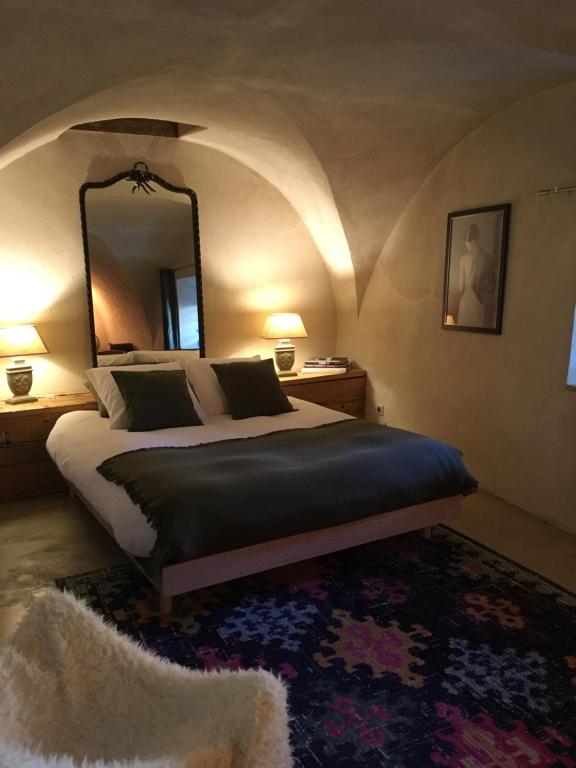 Le NoyerLa Suite Lou的一间卧室配有一张带镜子和地毯的床