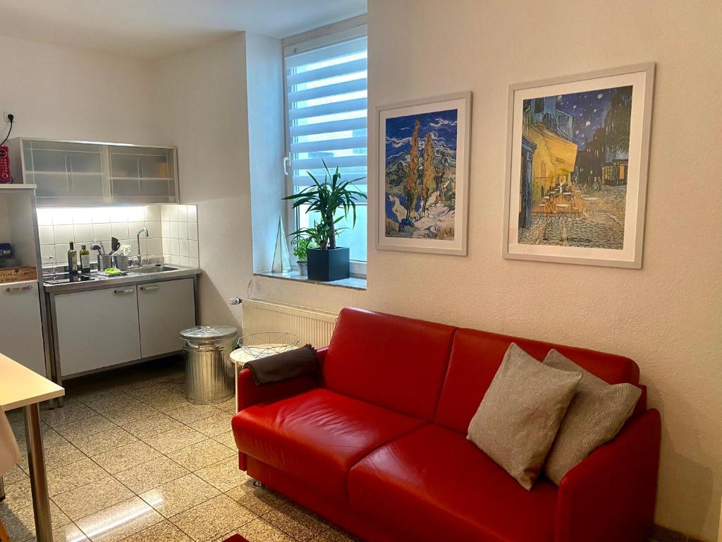 亚琛Chez Coco Apartment 1 Aachen的一间带红色沙发的客厅和一间厨房