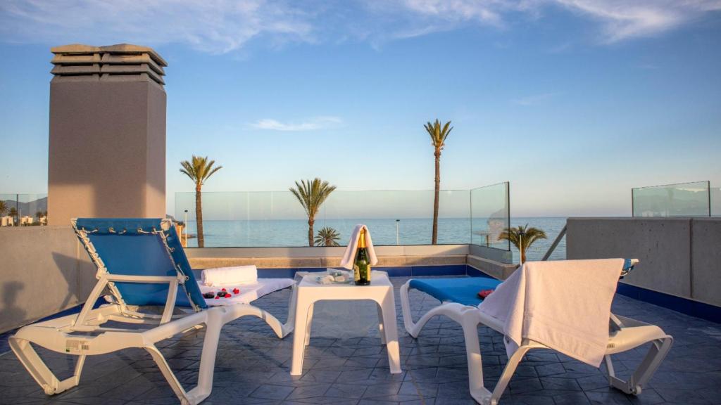 马萨龙港Apartamentos Buendía的阳台上配有两把椅子和一张桌子,享有海景