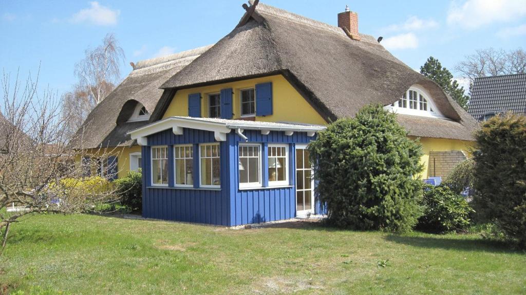 维克维乔特温克尔自助服务式酒店的黄色和蓝色的房子,带有茅草屋顶