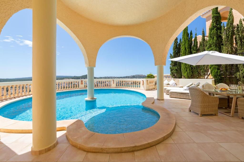 圣蓬萨Meerblick Villa "Buena Vista" in Santa Ponsa, Mallorca的度假村的游泳池,配有桌椅