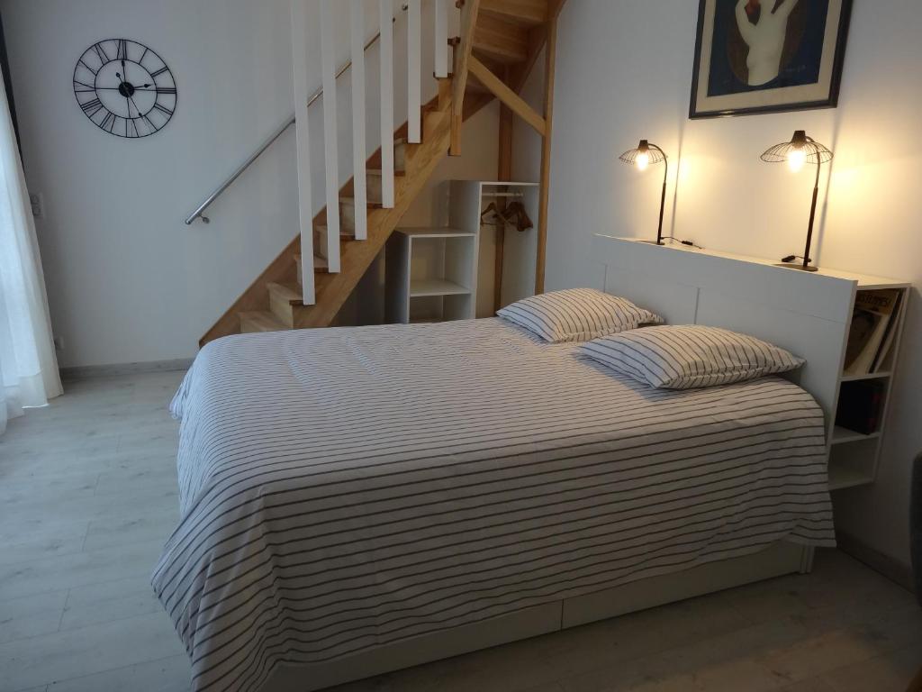 布雷索塞尼Les Petites Tuileries的一间卧室配有带2个枕头的床和楼梯