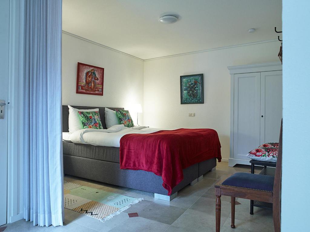 登博斯Studio # Het Pauwennest的一间卧室配有一张带红色毯子的床