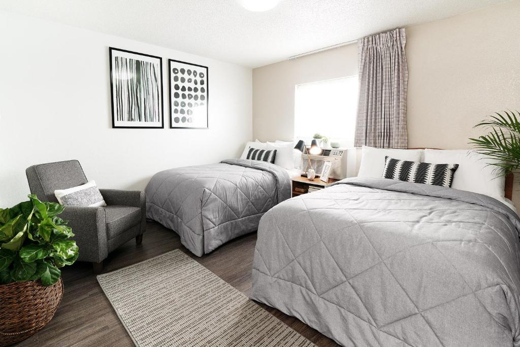 印第安纳波利斯InTown Suites Extended Stay Indianapolis IN - Traders Point的一间卧室配有两张床和椅子