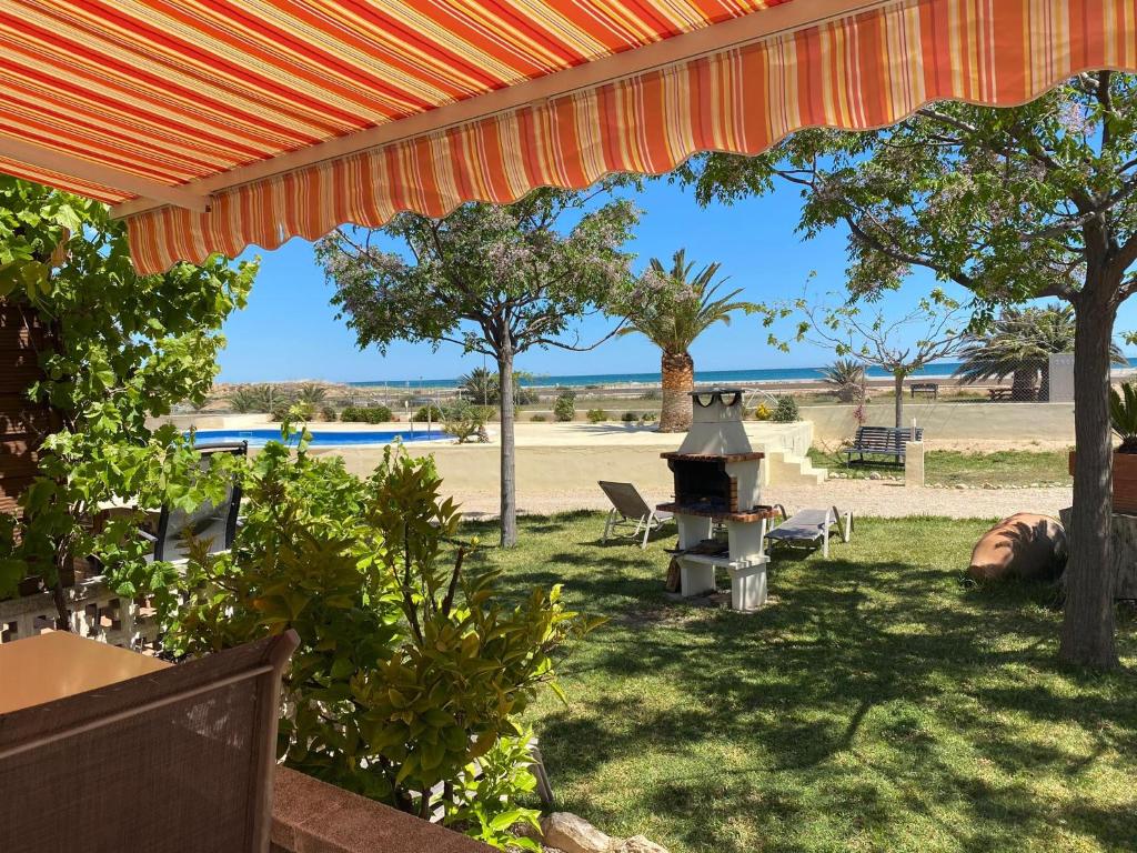 霍斯皮塔勒·德尔英福Beach Resort La Margarita的一个带烧烤架和树木的后院和海滩