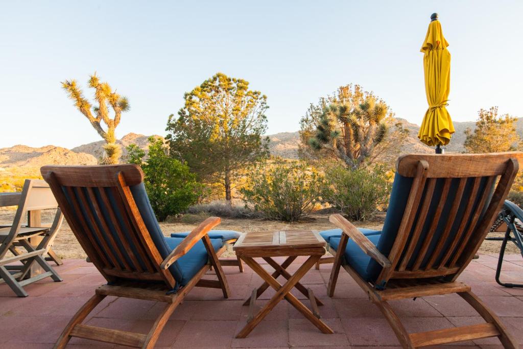 约书亚树@ Marbella Lane - 10 Acres Oasis Desert Retreat!的天井上配有两把椅子、一张桌子和一把遮阳伞