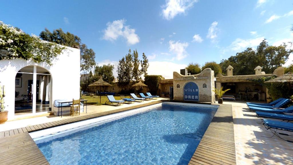 Ghazoua大巴别墅酒店的一座房子旁带躺椅的游泳池