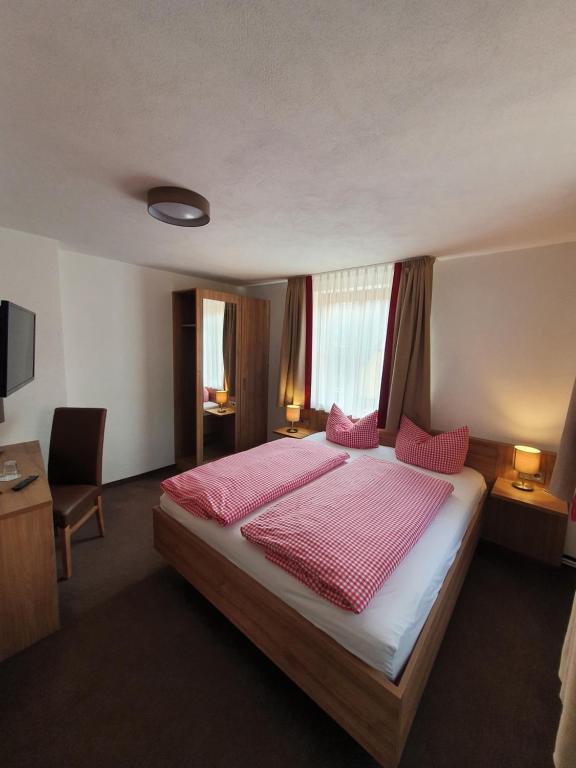 罗滕堡老木匠酒店的一间卧室配有一张带粉红色床单的大床