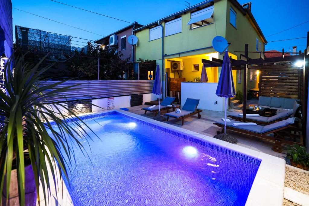 扎达尔Apartment Rustica Zadar with exclusive use of the pool-ground floor的夜间在房子前面的游泳池