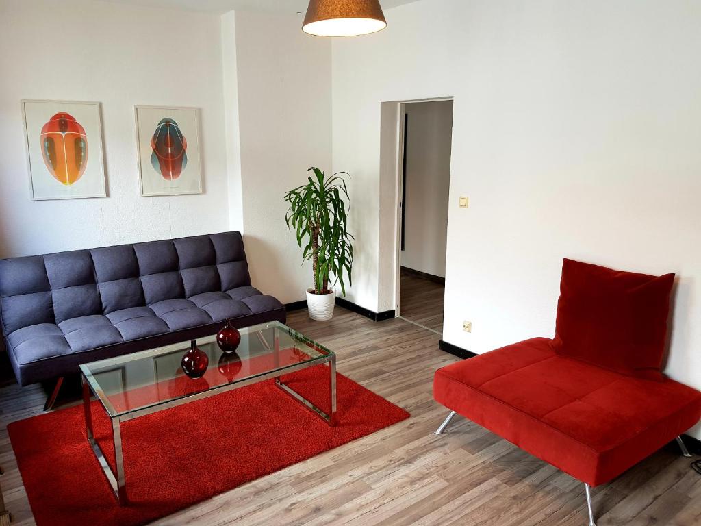 柏林可卡洛奇塔瑟甜蜜公寓的客厅配有蓝色的沙发和红色的椅子