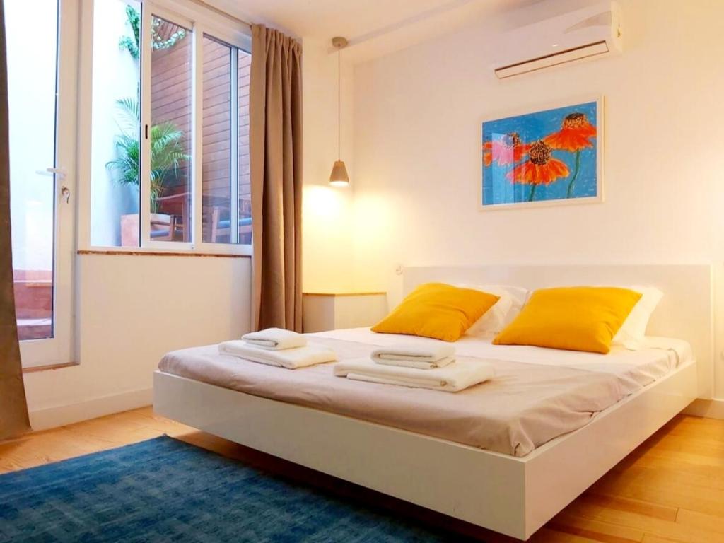 塔维拉Casa do Arco by HnM的一间卧室配有一张带黄色枕头的床和一扇窗户