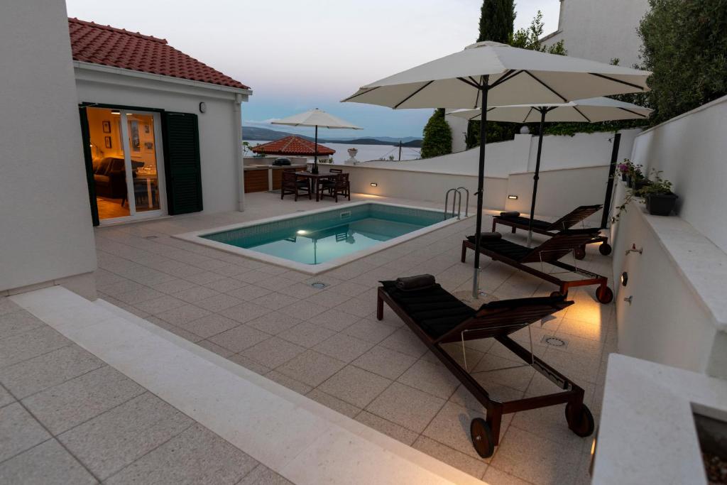 斯托莫斯卡Villa Solenta s grijanim bazenom的庭院设有游泳池、两把椅子和一把遮阳伞
