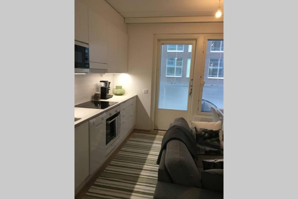 伦派莱MODERNI YKSIÖ HUIPPUSIJAINNILLA!的厨房配有白色橱柜、沙发和窗户。