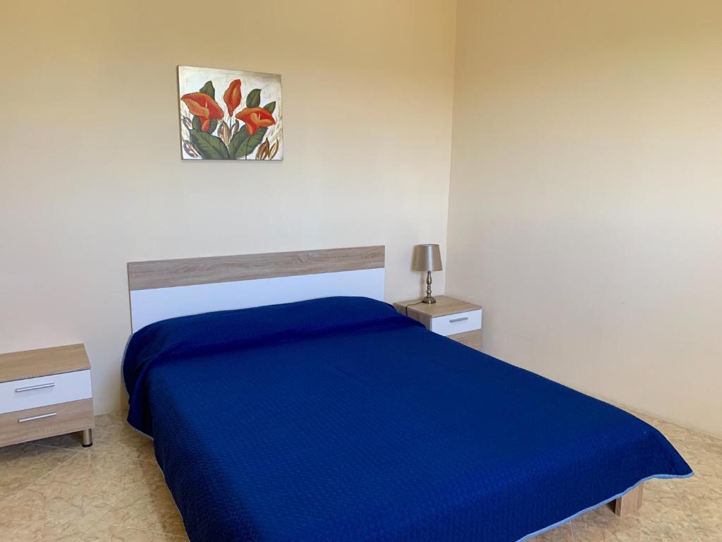Santa LuċijaVillage Apartments的卧室配有蓝色的床和墙上的绘画作品