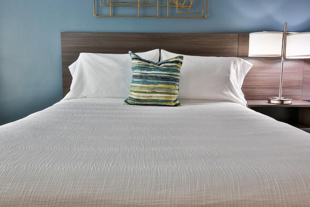 圣乔治小木屋汽车旅馆的一张白色的大床,上面有条纹枕头