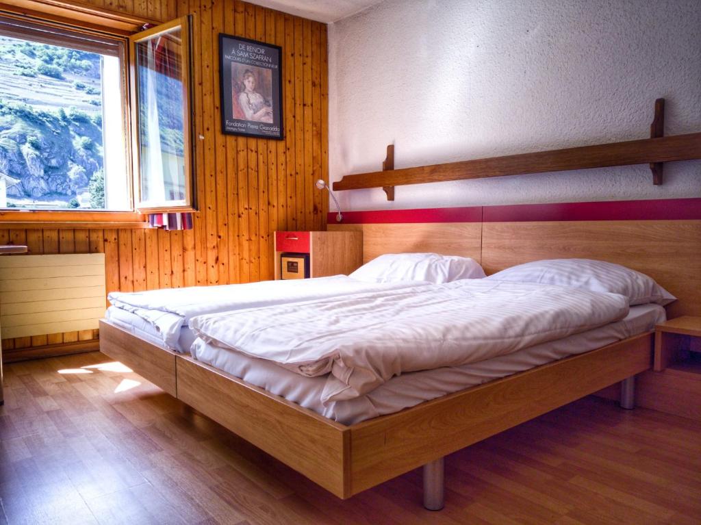 马蒂尼威尔Hotel du Stand的木制客房内的一间卧室配有一张大床