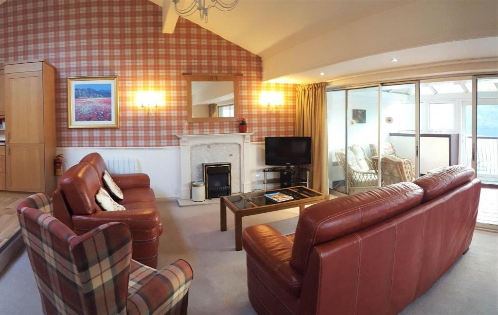 金洛赫兰诺赫Loch Rannoch Highland Lodge 44的客厅配有皮革家具和壁炉