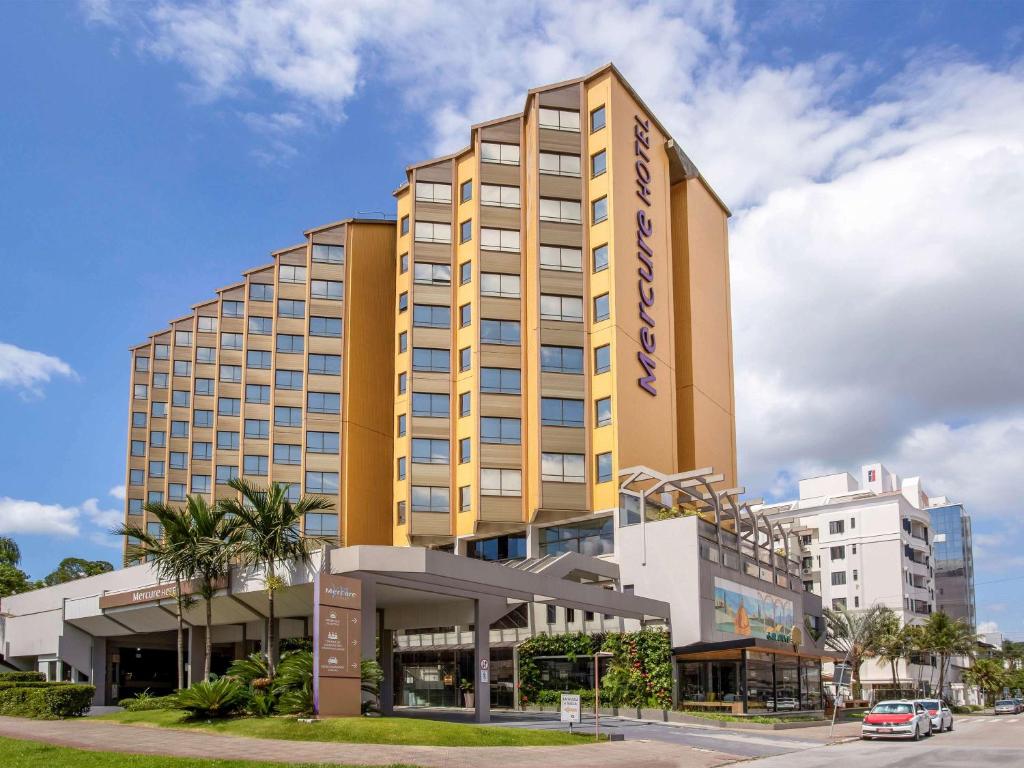 弗洛里亚诺波利斯Mercure Florianópolis的一座高大的黄色建筑,设有购物中心