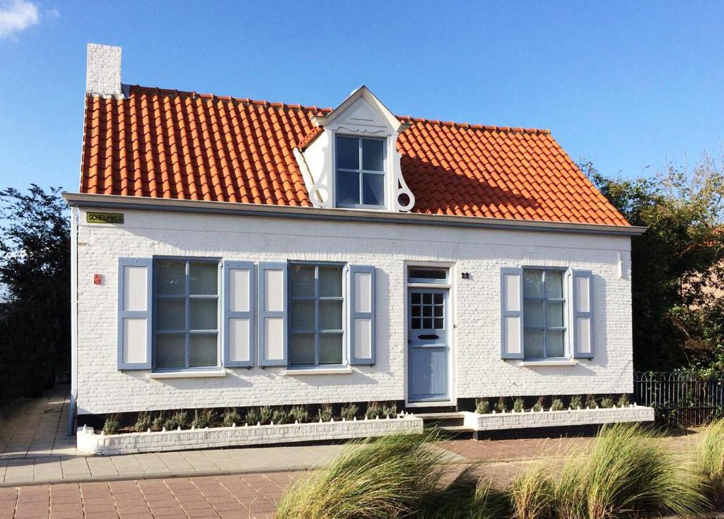 栋堡B&B Zee van Tijd Domburg的一座白色的小房子,拥有橙色的屋顶