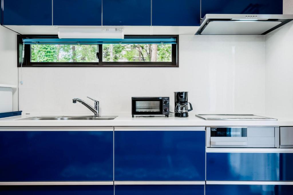 白马村Sali's House的厨房配有蓝色橱柜和水槽