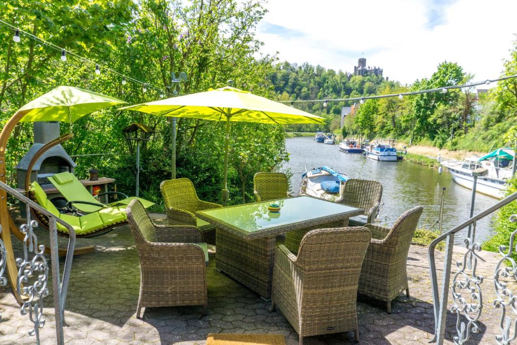 兰施泰因Ferienhaus auf der Schleuseninsel的河边的桌椅和遮阳伞