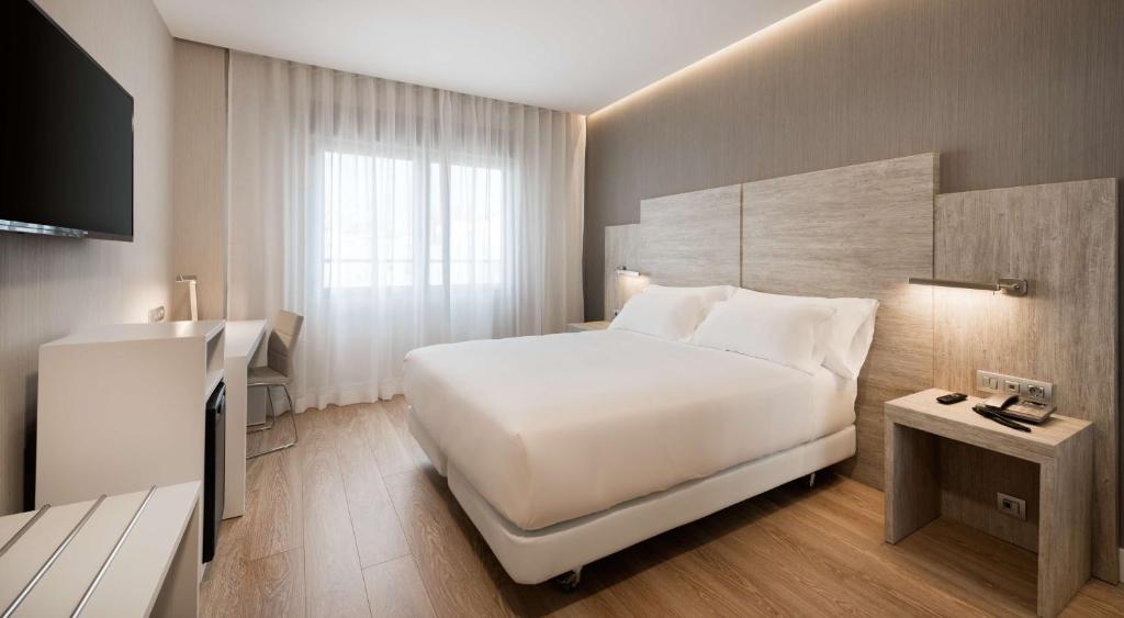 马德里NH马德里贝里酒店的酒店客房设有一张大床和一台电视。