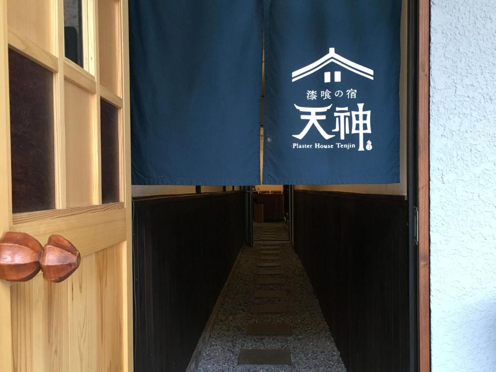 松江市Shikkuinoyado Tenjin的一条带蓝色旗帜和鞋子的长走廊
