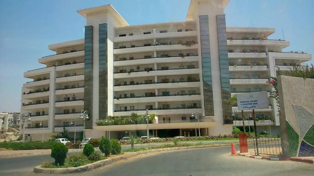 阿加迪尔Marina Agadir appartement standing 90m2 + piscine的一座大型公寓楼,前面设有停车场