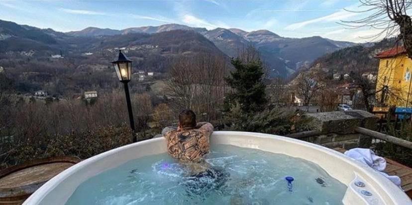 廖卢纳托Casa Benassi Rooms, Apartament & Suite con Piscina panoramica e Wellness的山景按摩浴缸中的男士