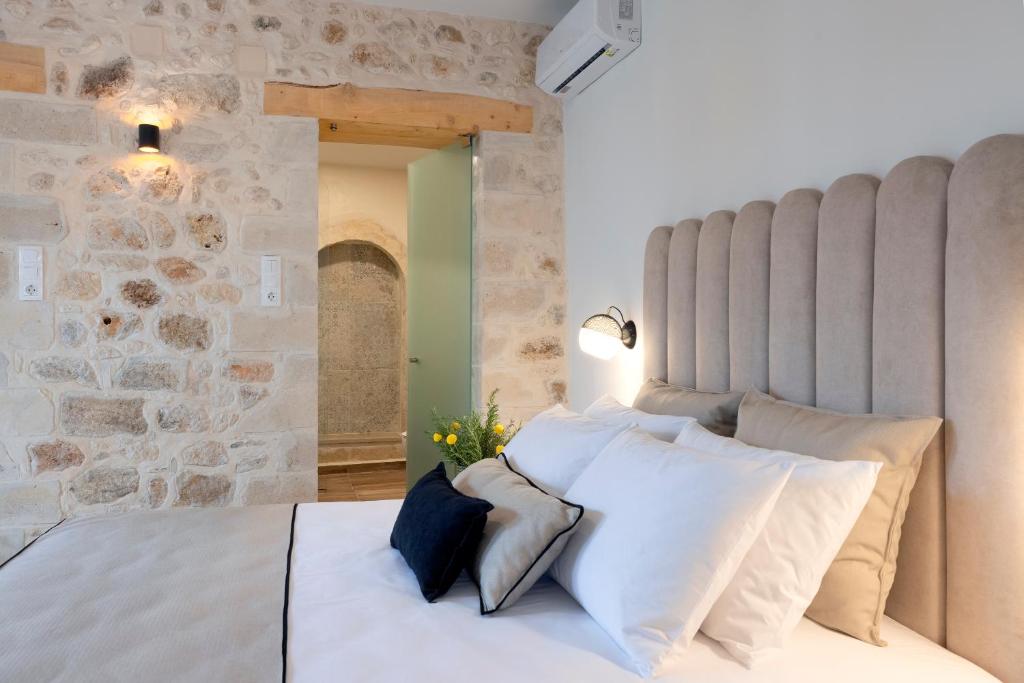 罗希姆诺CASA GIORGIO EXCLUSIVE SUITES的卧室配有白色的床铺和石墙