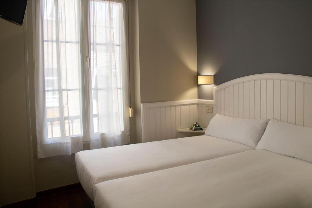 希洪Alda Miramar Rooms的卧室配有白色的床和窗户。