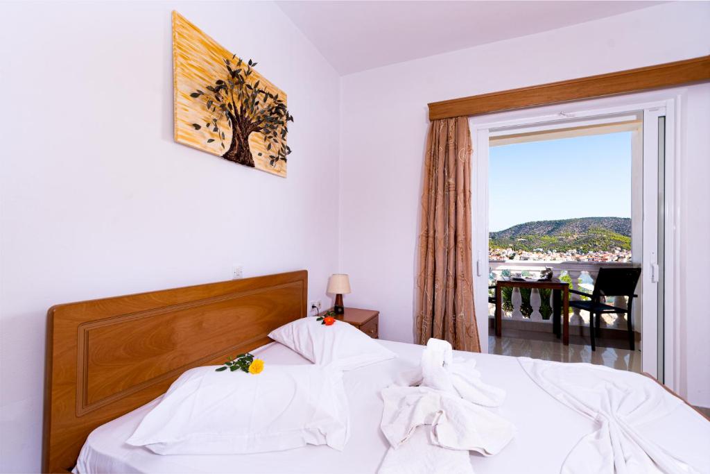 加拉塔斯Poros View的一间卧室配有一张带白色床单的床和一扇窗户。