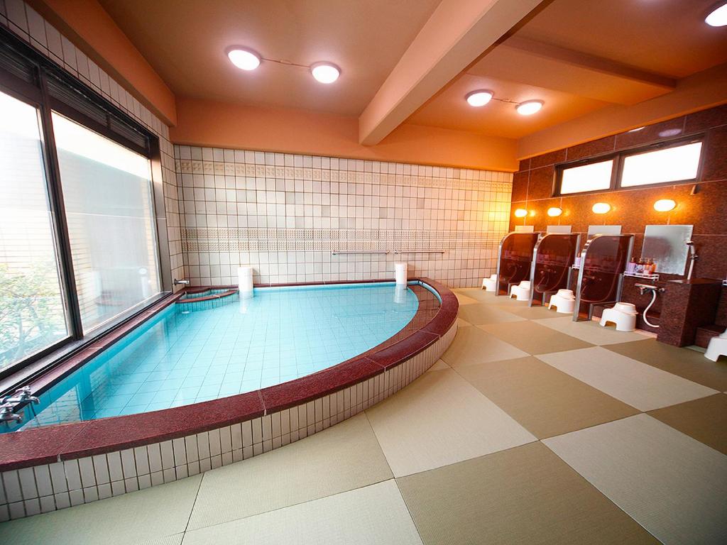 高知高砂酒店 的大型游泳池,位于带大窗户的房间内