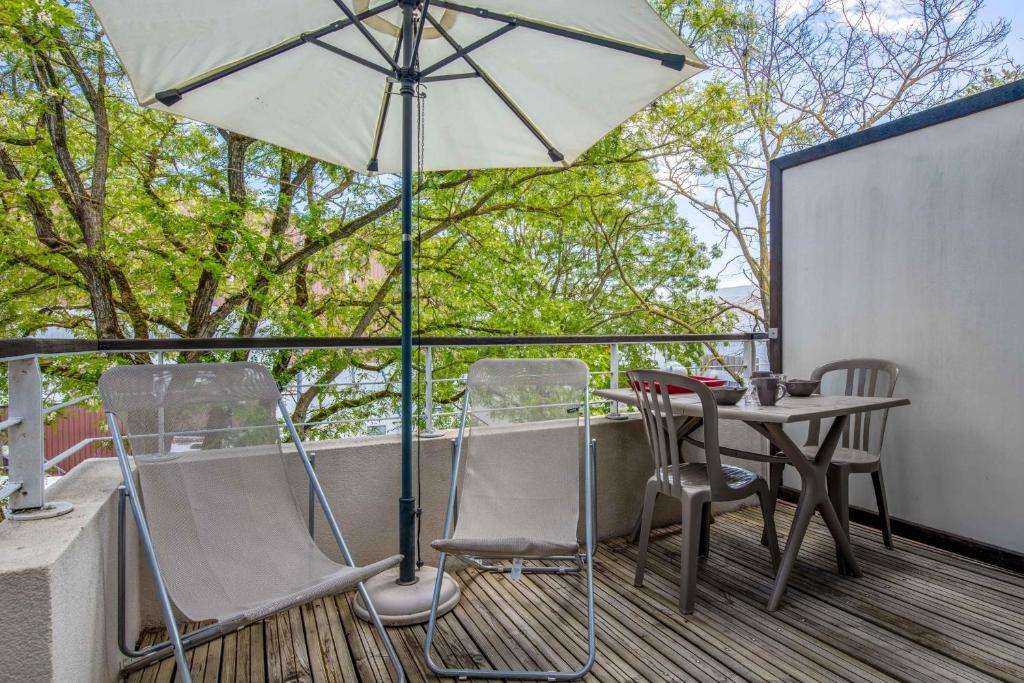 拉罗谢尔Appartement Dauphine - Welkeys的阳台配有桌椅和遮阳伞