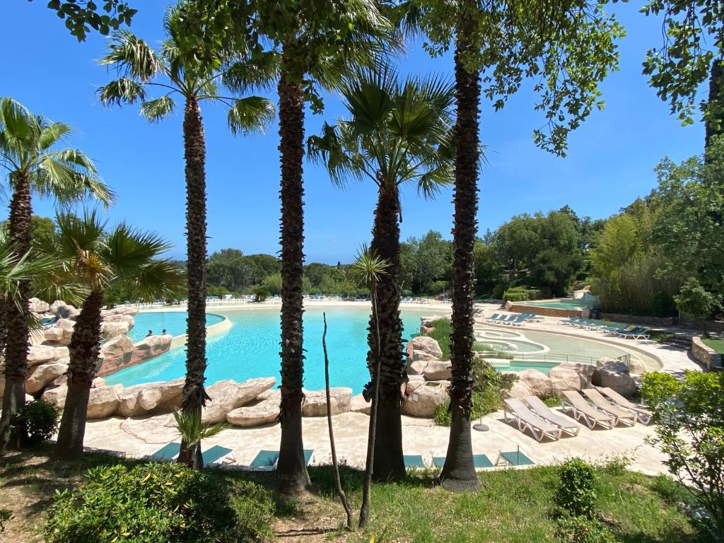 格里莫Domaine des Restanques, suite parentale ,vue mer.的度假村内棕榈树游泳池