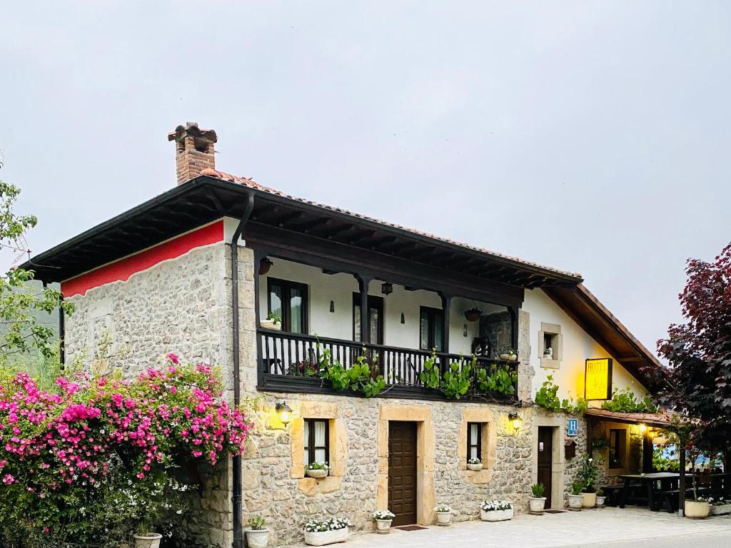 Avín阿尔达酒店的带阳台和粉红色鲜花的石头房子