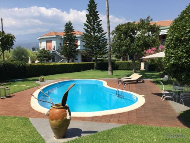 马斯卡利Villa con piscina esclusiva vista Etna的一座房子旁边的带花瓶的游泳池