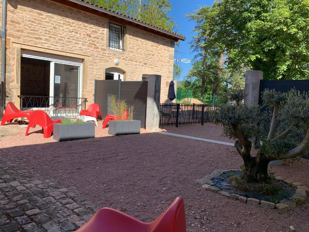 克卢尼La Maison Clémenso的一座建筑前的庭院,庭院里摆放着红色椅子和一棵树