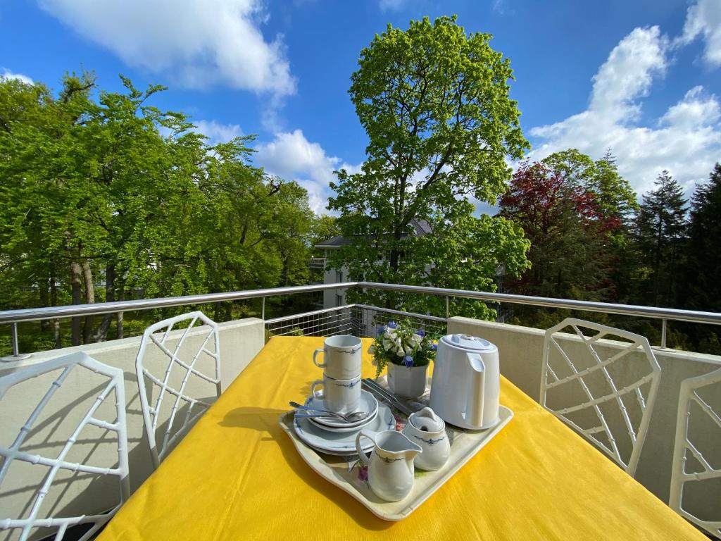 黑灵斯多夫Residenz Bleichröder - Ferienwohnung Cosima的阳台上的黄色桌子,上面有杯子和碟子