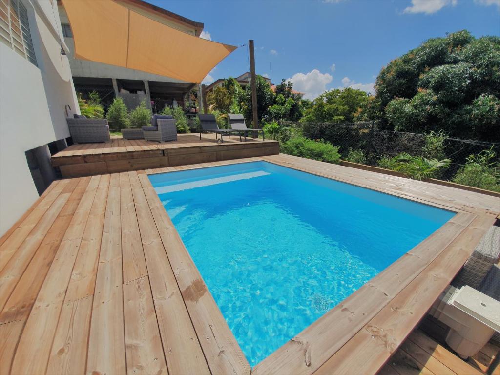 舍尔谢Kozycoco - Suite Kozy - séjour tropical au calme的一座带木甲板的游泳池,位于一座房子旁边