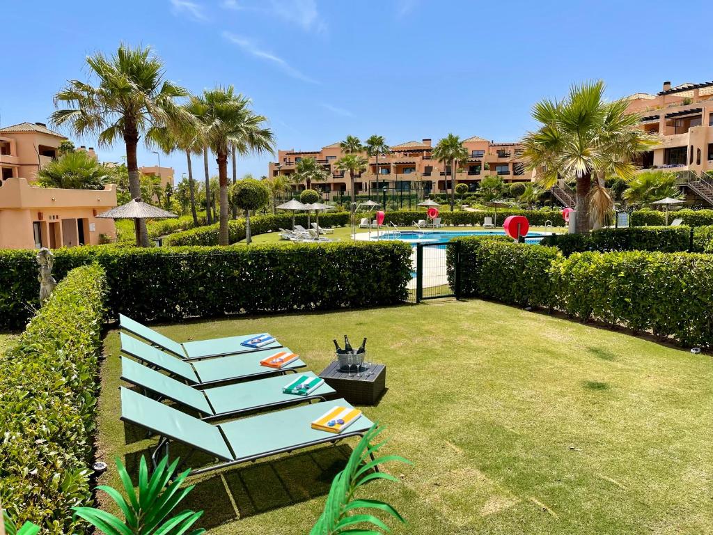 卡萨雷斯Casares Beach Golf Apartment With Private Garden Direct Pool Access的一个带蓝色长椅和游泳池的庭院