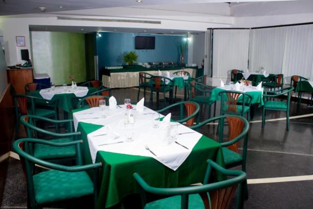 加拉加斯Hotel Chacao Cumberland的用餐室配有绿色的桌椅