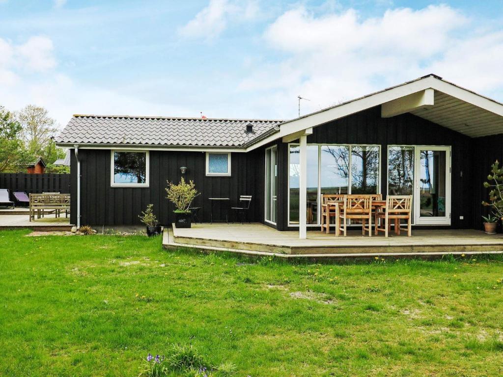 诺尔赫鲁普9 person holiday home in Hadsund的一间黑色的小房子,设有门廊和椅子