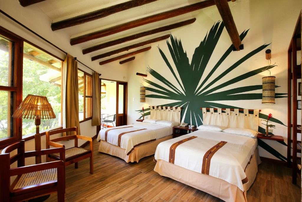 弗洛勒斯玛雅别墅酒店的卧室配有两张床,墙上挂着一个大植物