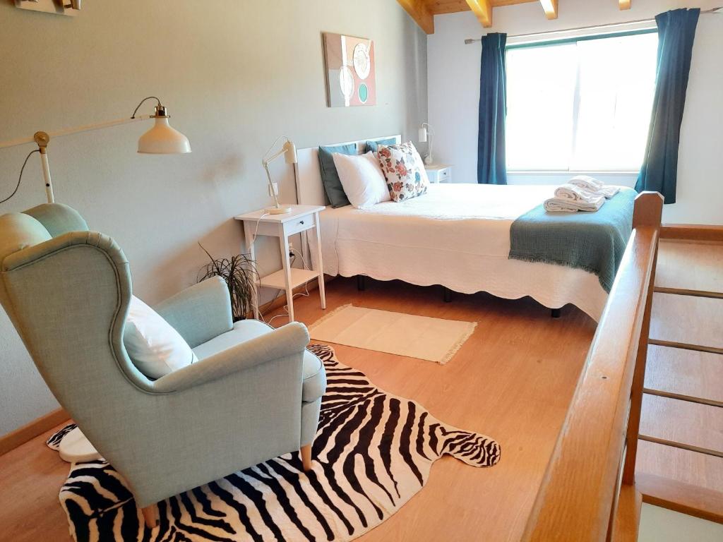 奥德赛克斯Apartamentos Mar I Odeceixe的一间设有一张床和一把椅子的房间,并铺有斑马地毯